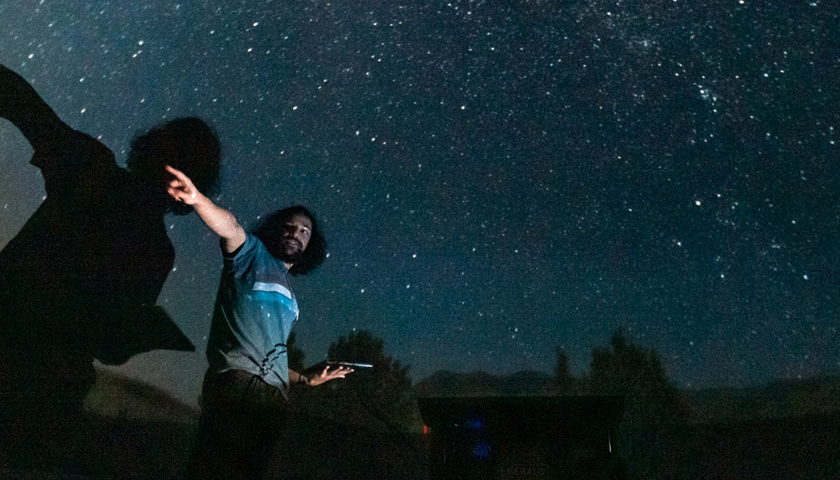 A lecturer pointing at a part of the galaxy displayed on the planetarium ceiling