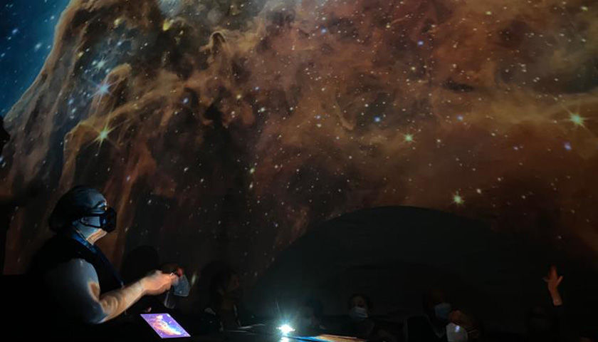 An academic stands in front of a projection of the Milky Way