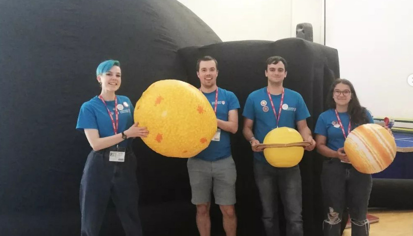 A group of student ambassadors holding an inflatable sun, Jupiter, and Saturn