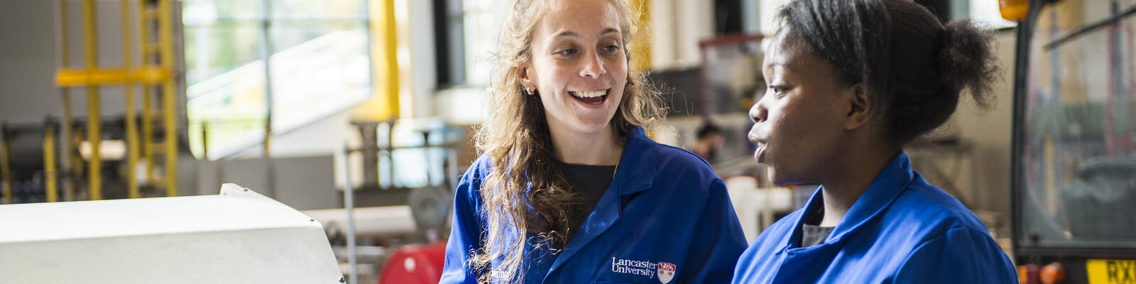 Two students in lab coats on in the mechanical engineering workshop