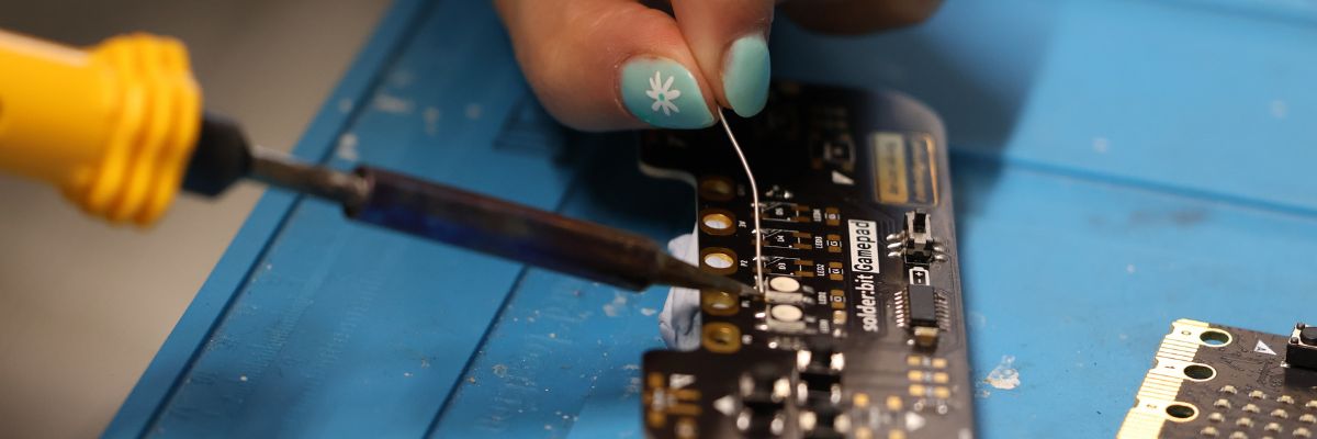 A person soldering onto a micro:bit board