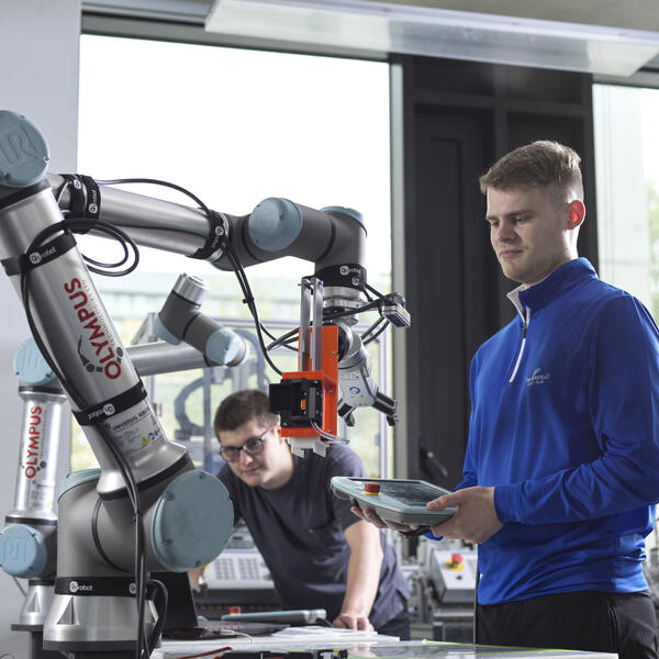 Two students using the robotics arms in the mechanical engineering workshop