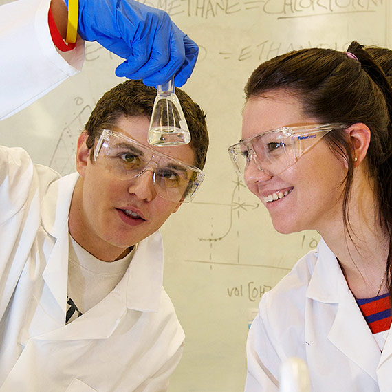 Two students looking at a beaker