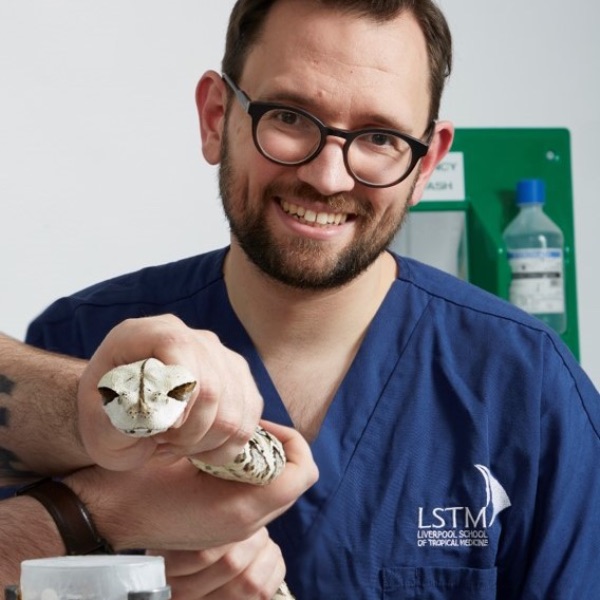 Professor Steven Hall holds a snake to milk its venom.