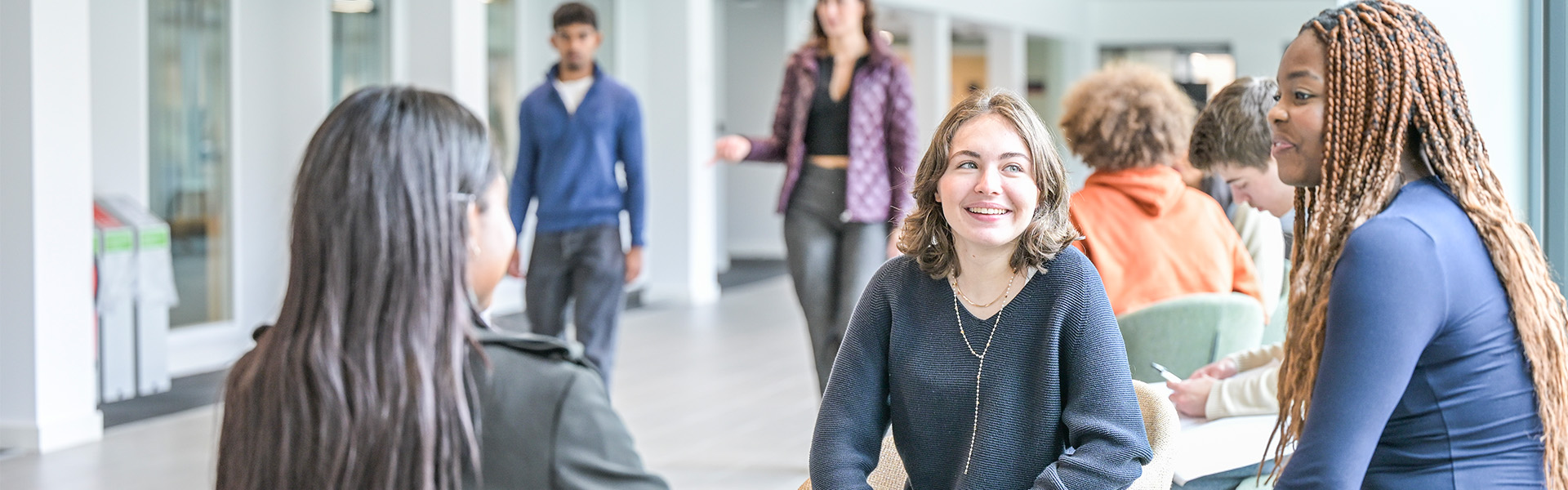 Students sit and chat in a bright, modern building