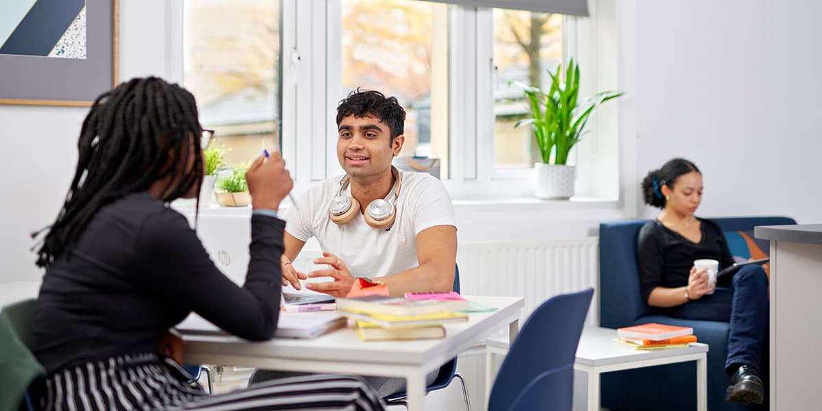 Students working and chatting at a table in a bright, airy kitchen dining room