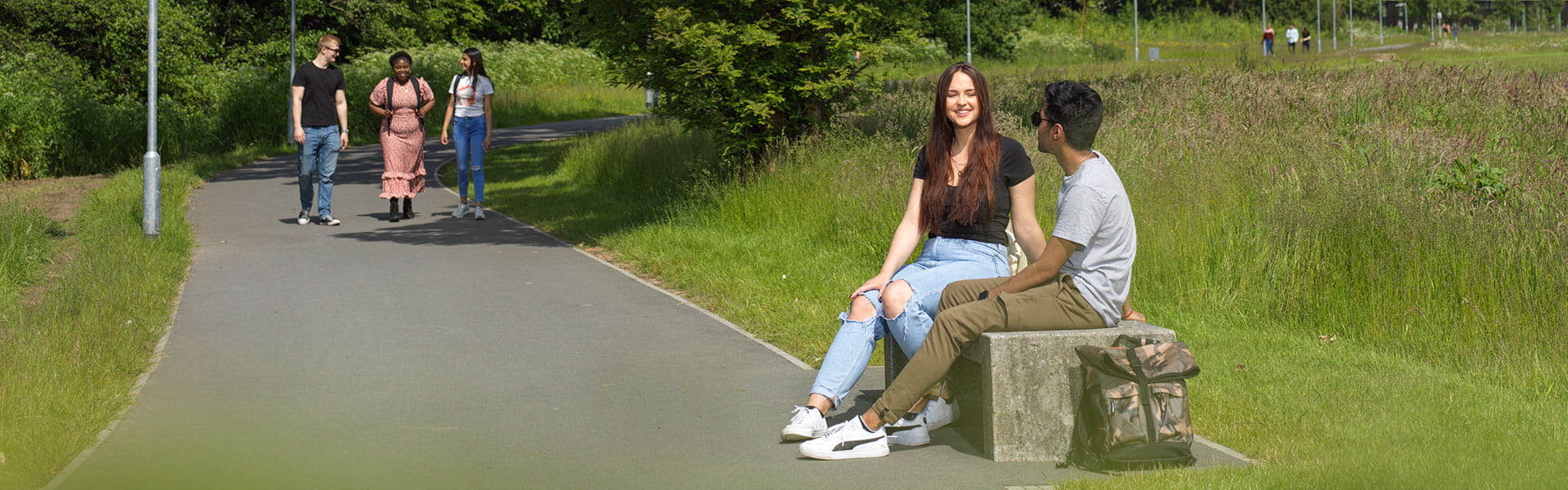 Two students sit surrounded by greenery