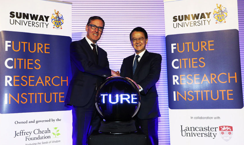 Alan Milburn and Tan Sri Dato’ Seri standing on a podium shaking hands