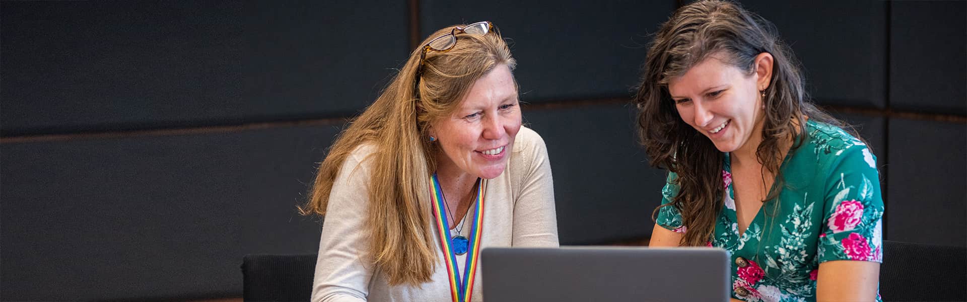 Two people in a discussion looking at a laptop