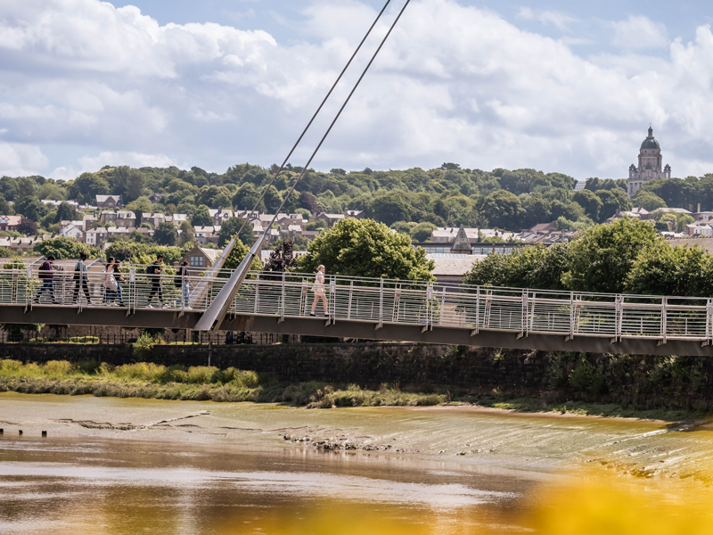 Six students walking across the Millennium Bridge in Lancaster city entre
