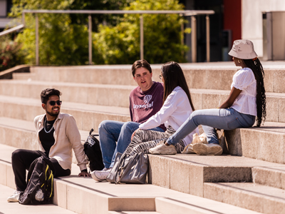 Four students sitting on the steps in Alexandra Square in the summer