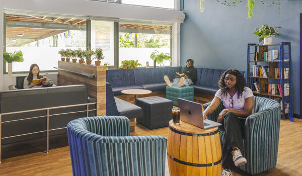 Students sat studying around a modern, stylish college social space.