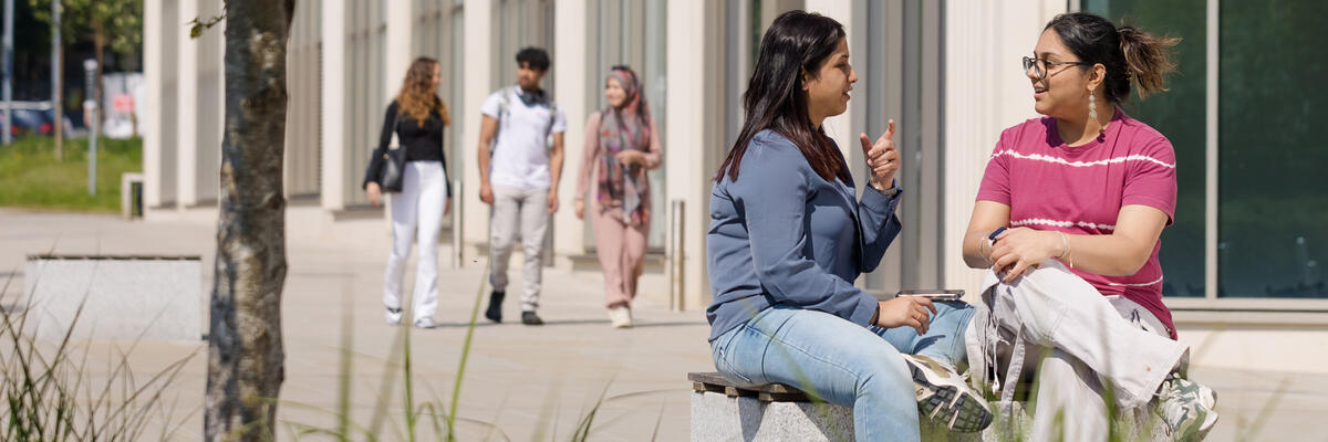 Students sitting chatting outside of the management school building