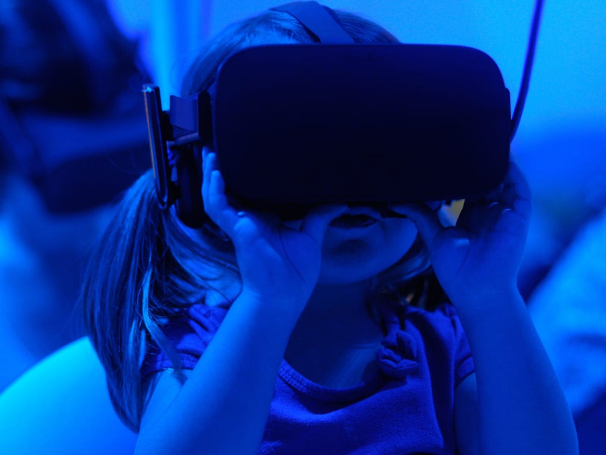 Two hands painted in lots of colours reach out.