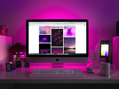 A computer desk with pink ambient lighting.