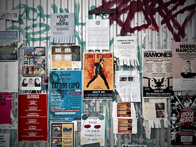 Lots of posters on a wooden wall.