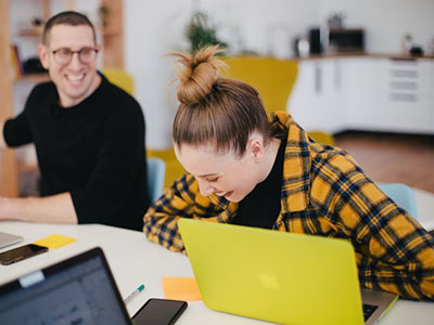 A woman laughing while sat at her laptop.