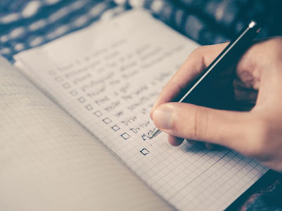 Someone writing a list with checkboxes.