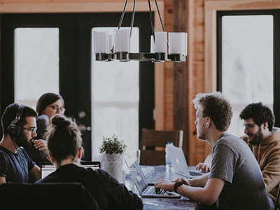 A group of people working on laptops around a large table.