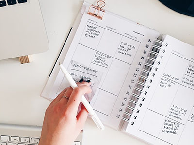 Some one holding a pen over a notepad.