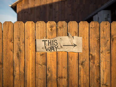 A wooden fence with a sigh saying This Way.