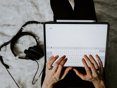 A woman typing notes on her iPad.
