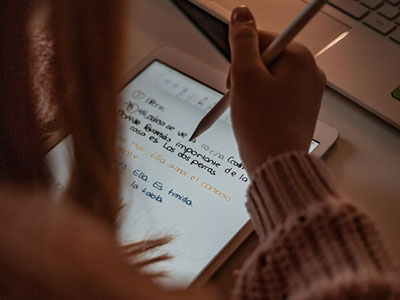 A woman writing notes on an iPad.