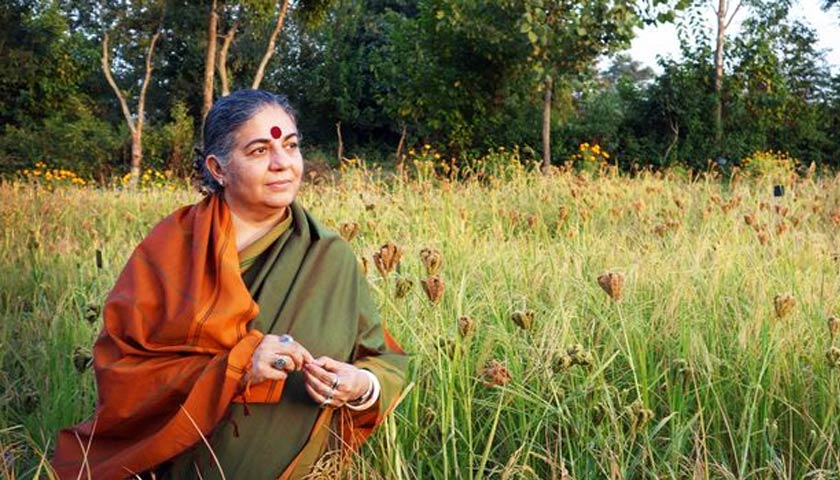 Vandana Shiva in a field of long grass and wildflowers