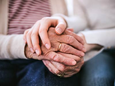 two hands one of an older person and one younger comforting them