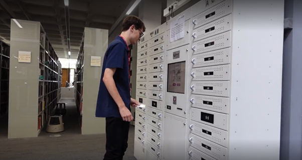 Library ambassador using student id swipe card to borrow a laptop from the laptop loan stand.