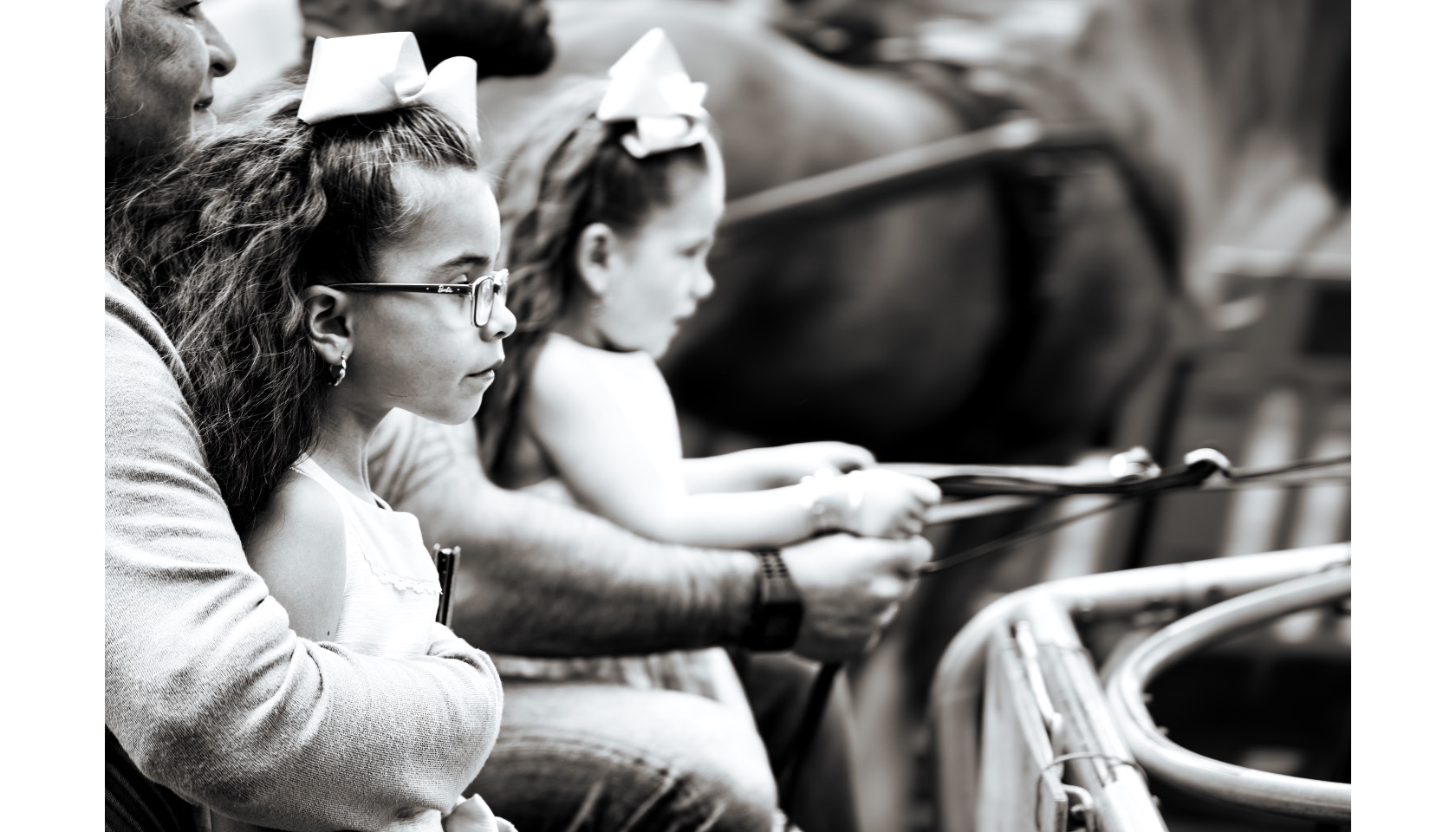 A woman and two young girls sitting on a wagon.