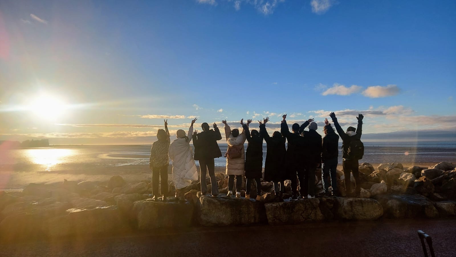Students silhouetted by the sunset at Morecambe Bay