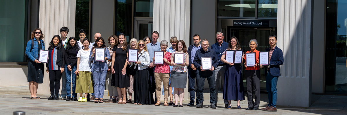 A group of staff outside the Management school holding certificates