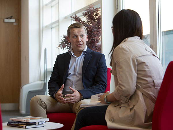 Two people sitting on red seats having a meeting.