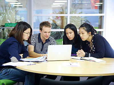 Group of students working at desk looking at a laptop