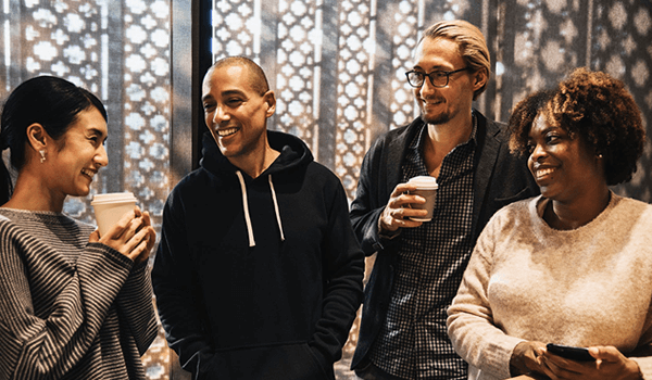 A group of people standing talking and drinking coffee 