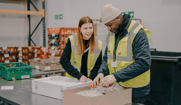 Two people packing food in a warehouse