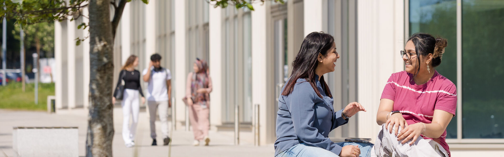 Pair of students sitting outside the Management School building