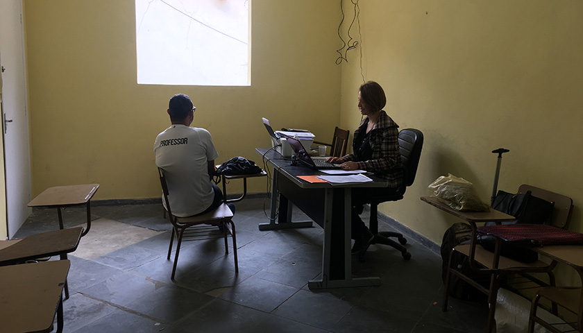 A woman sitting working behind a desk, and a man sitting opposite her