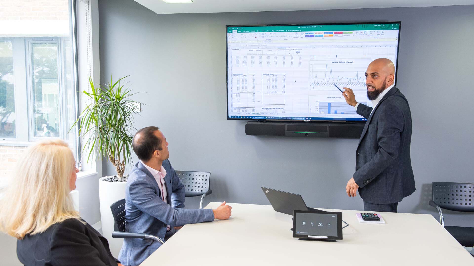 Man in suit giving presentation to two colleagues