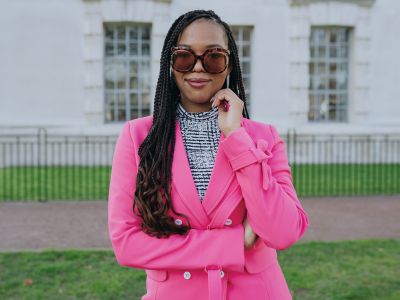 Kelsey wearing a pink jacket and large framed sunglasses