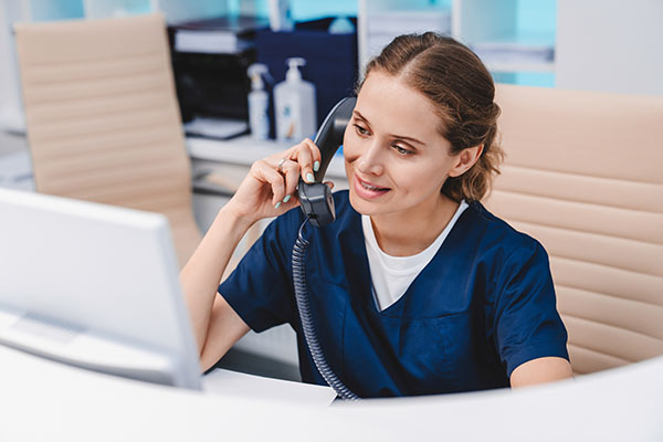 A healthcare worker sitting at her desk on the telephone. 