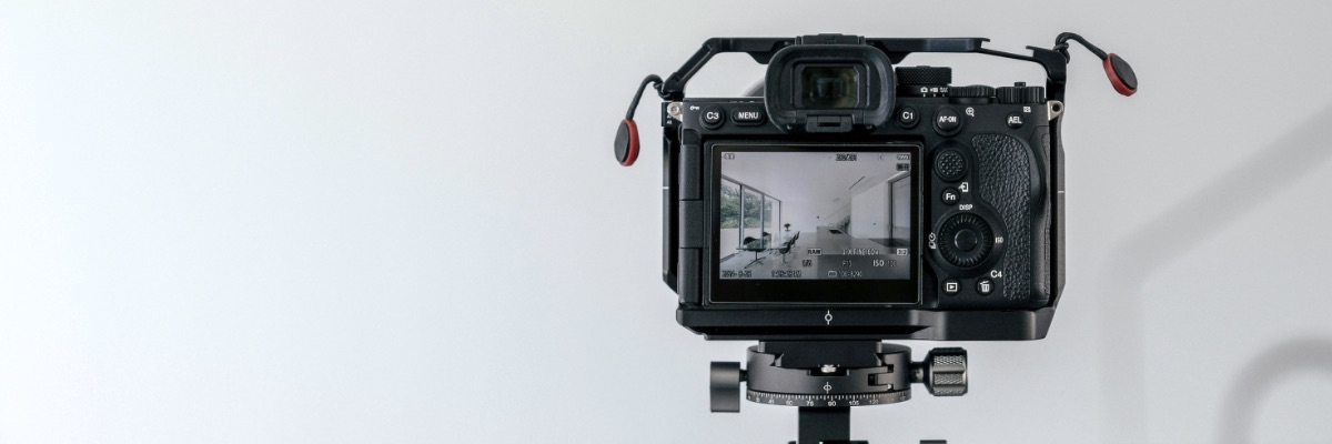 A camera on a tripod in a blank white photography studio