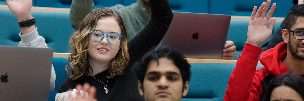 Students raise their hands in a lecture
