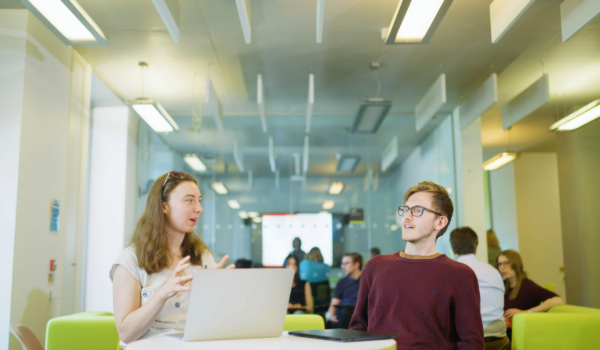 Students working at a table with a laptop 