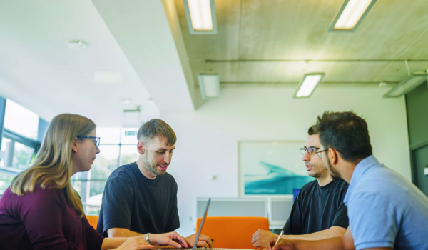 Students and postdoc working together round a table