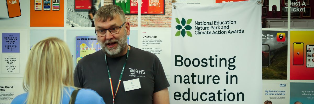 Simon from Nature Parks at a stand with a Nature Parks banner talking to an attendee at the MBC conf