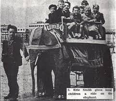 black and white newspaper image of man leading mechanical elephant through morecambe with children
