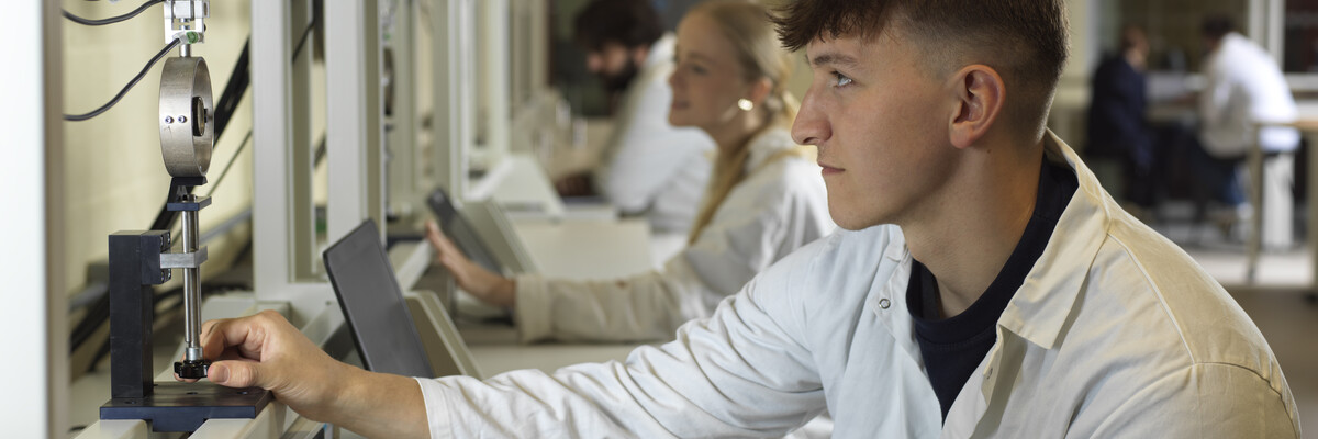 A student uses a piece of complicated equipment in an Engineering laboratory.