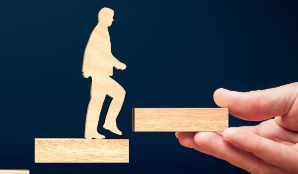 Figure taking steps being given a helping hand upwards. 